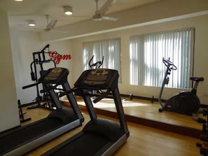 Une salle de sport équipée de tapis de course, d’un vélo elliptique et d’un vélo d’appartement.