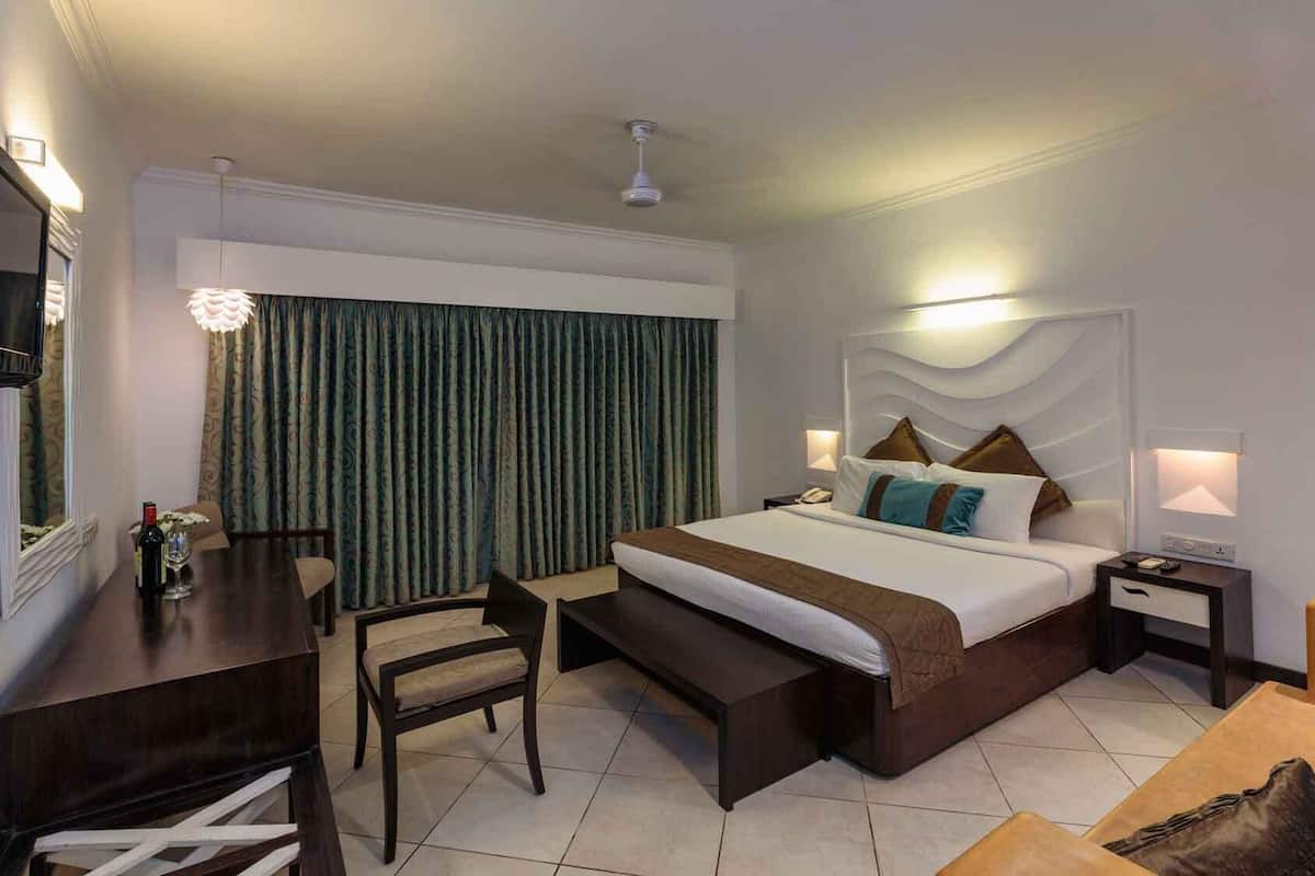 A hotel room with a bed, bedside tables, a desk, and a chair.