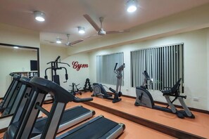 Ein Fitnessstudio mit Laufbändern, Crosstrainern und einem Wandspiegel.
