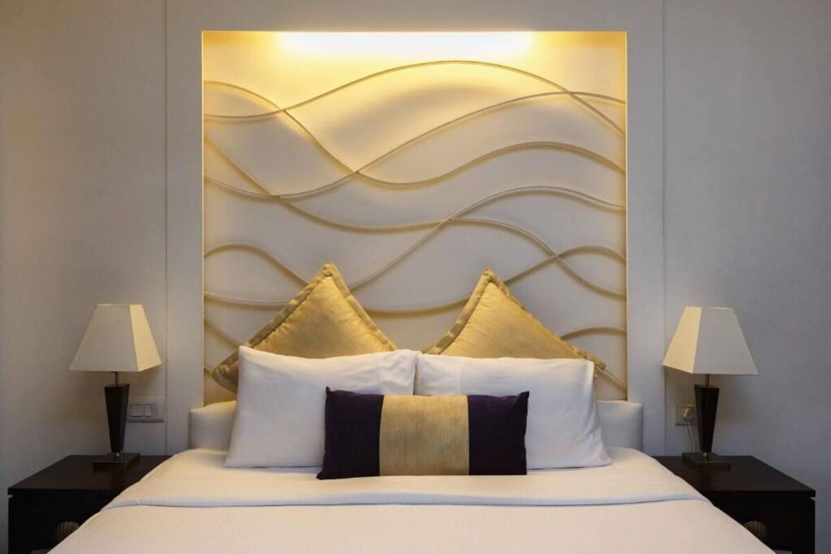 A hotel room with a bed, two bedside tables with lamps, and a decorative wall panel.