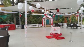 An outdoor patio area with tables and chairs, a white canopy, and red and white decorations. - Sonesta Inns Beach Resort - Candolim Beach (Candolim)
