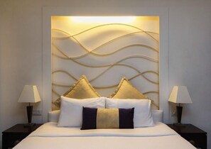 Una habitación de hotel con una cama, dos mesitas de noche con lámparas y un panel decorativo en la pared.