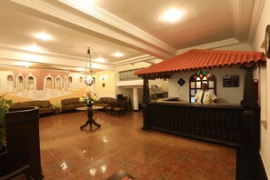 A lobby with a reception desk, a staircase, and a seating area with a vase of flowers. - Sonesta Inns Beach Resort - Candolim Beach (Candolim)