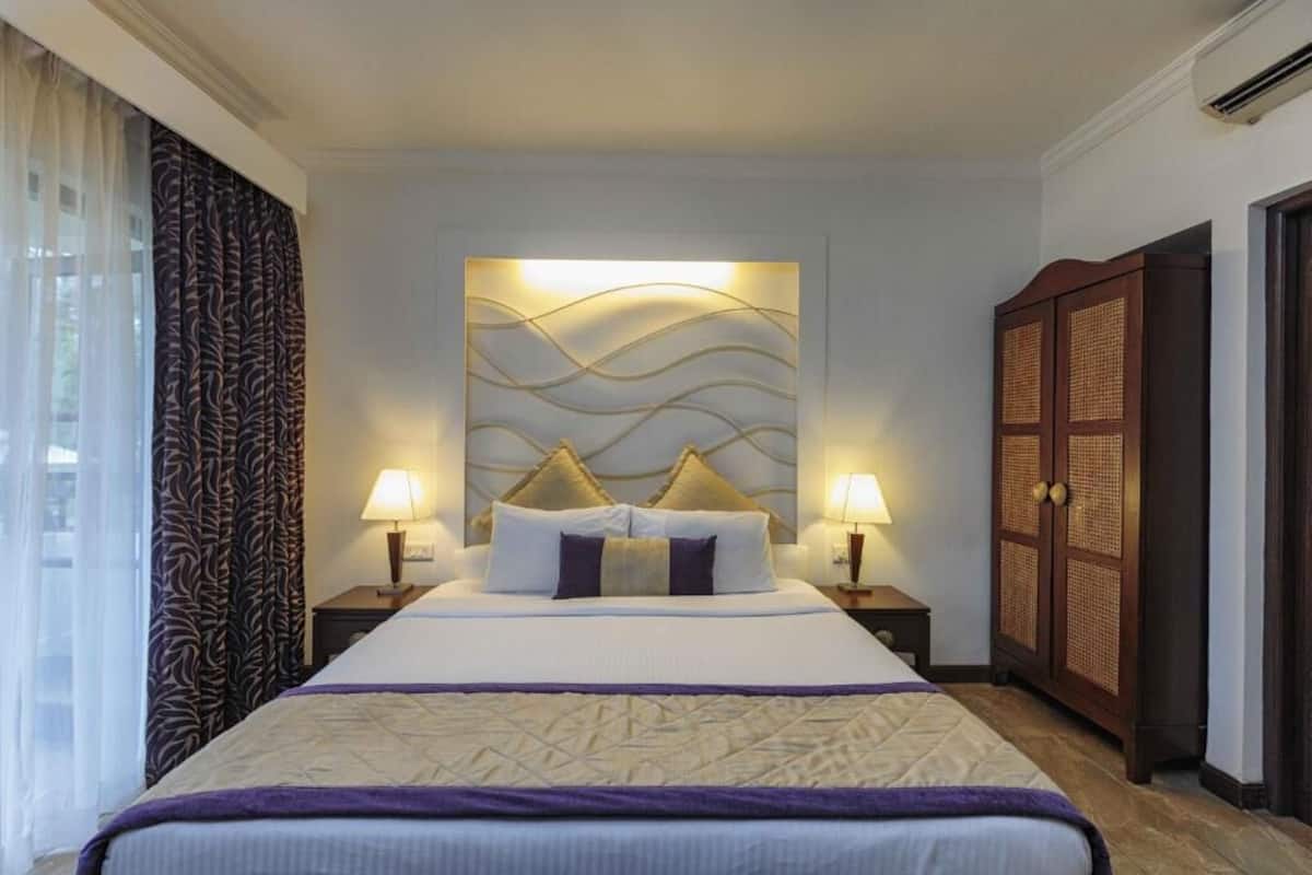 Ein Hotelzimmer mit einem großen Bett, zwei Nachttischlampen, einem verzierten Kopfteil und einem Kleiderschrank.