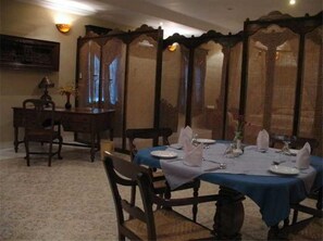 A dining room with a blue tablecloth, wooden chairs, and a decorative screen. - Sonesta Inns Beach Resort - Candolim Beach (Candolim)