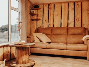 Ein Holzinterieur mit einer Couch, einem runden Holztisch und Regalen an der Wand.