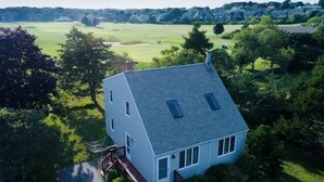 Une maison avec un toit en pente, une petite terrasse et une vue sur un champ verdoyant.