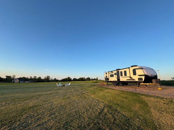 A recreational vehicle (RV) parked in a grassy field with a clear sky.