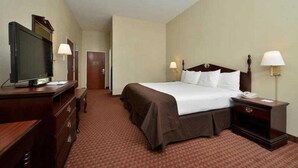 Une chambre d’hôtel avec un lit, des lampes de chevet, un téléviseur posé sur une commode et une porte.