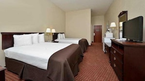 Quarto de hotel com duas camas, uma cômoda, uma televisão e uma porta que dá para outro espaço.