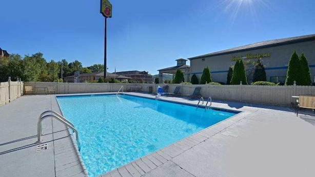 Piscina retangular com uma escada de metal de um lado, rodeada por um deck de concreto.