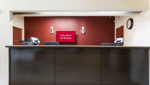 Un comptoir d’accueil avec un panneau indiquant « Wi-Fi gratuit dans toutes les chambres », une horloge et une caméra de surveillance.