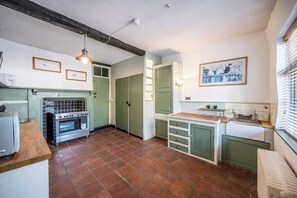 A kitchen with green cabinets, a tiled floor, a stove, and a sink.