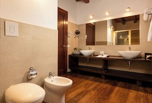A bathroom with a toilet, bidet, two sinks, a mirror, and wooden flooring. - The Paradise Dambulla (Kandalama)