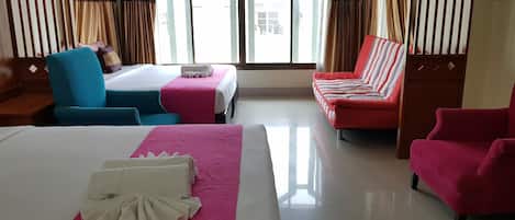 A hotel room with two beds, a sofa, a chair, and a large window.