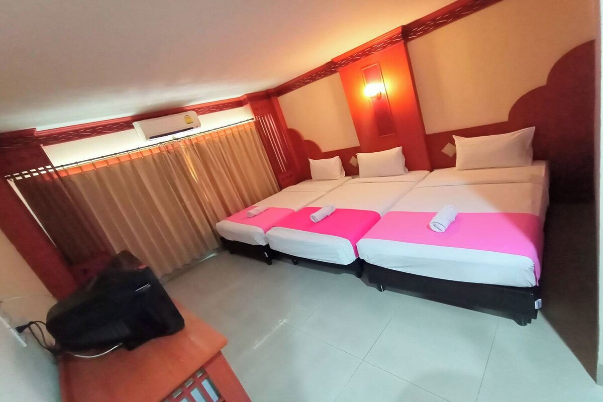 A hotel room with a large bed, a desk, and a chair.