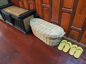 A wicker ottoman and a pair of yellow flip-flops on a wooden floor. - Poonsook Phitsanulok Hotel SHA Plus+ by Zuzu (Phitsanulok)