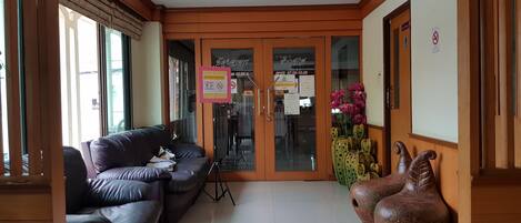 A lobby with a leather sofa, a cactus sculpture, and a wooden door with glass panels.