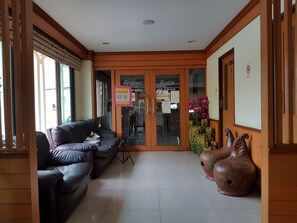 A lobby with a leather sofa, a cactus sculpture, and a wooden door with glass panels. - Poonsook Phitsanulok Hotel SHA Plus+ by Zuzu (Phitsanulok)