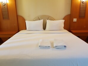 A neatly made bed with two pillows and two folded towels. - Poonsook Phitsanulok Hotel SHA Plus+ by Zuzu (Phitsanulok)