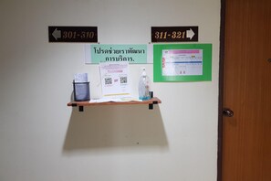 Un mur avec des panneaux d’indication, une étagère avec des documents, un code QR et un tableau d’affichage vert.