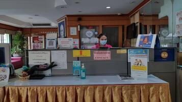 A reception desk with informational posters, a contact sign, and a QR code.
