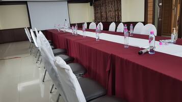 A conference room with a long table, chairs, water bottles, and a projector screen.