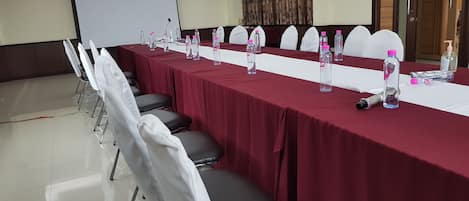 A conference room with a long table, chairs, water bottles, and a projector screen.