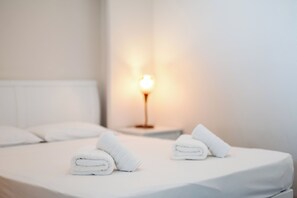 A neatly made bed with white linens and two rolled towels placed on it. - Pontikonissi Adults Only (Corfu)