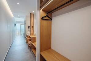 A modern hotel corridor with a wooden bench, a hairdryer, and a hanging black hanger. - Pontikonissi Adults Only (Corfu)