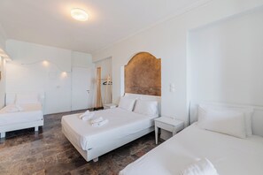 A hotel room with three beds, a wooden headboard, and a stone floor. - Pontikonissi Adults Only (Corfu)