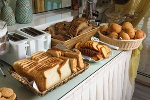 A breakfast buffet with various breads, pastries, and a toaster. - Pontikonissi Adults Only (Corfu)