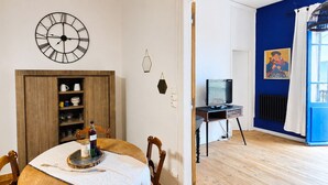 Una habitación con una mesa de comedor, sillas, un reloj de pared, un televisor y una pared decorada en azul.