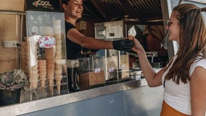 Un camion-restaurant où l’on vend de la crème glacée, avec un comptoir où sont exposés des cornets et une personne qui sert de la crème glacée à un client.
