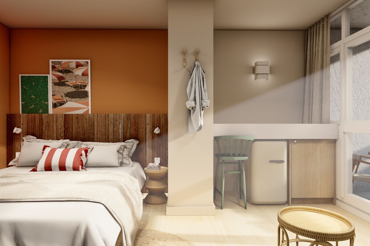 A bedroom with a bed, a nightstand, a wall-mounted towel rack, and a small table with a chair.