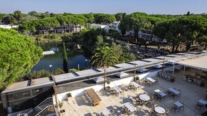A rooftop terrace with outdoor seating, a view of a lake, and surrounding greenery. - La Grande Motte "Le Ponant" (La Grande-Motte)