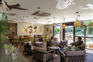 A café with wooden furniture, a bar area, and a view of greenery outside. - La Grande Motte "Le Ponant" (La Grande-Motte)