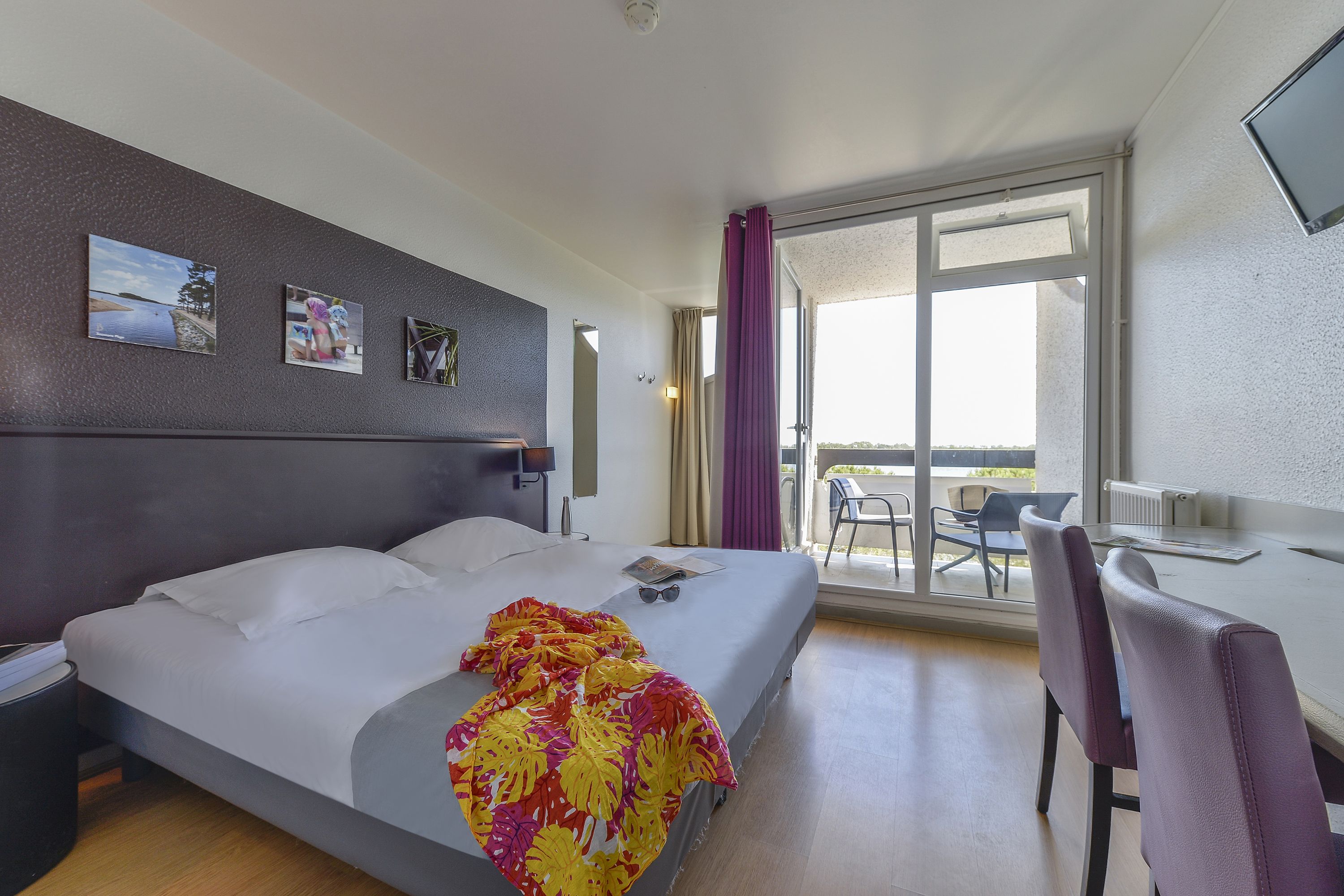 Ein Hotelzimmer mit Bett, Schreibtisch, Stuhl und einem Balkon mit Blick.