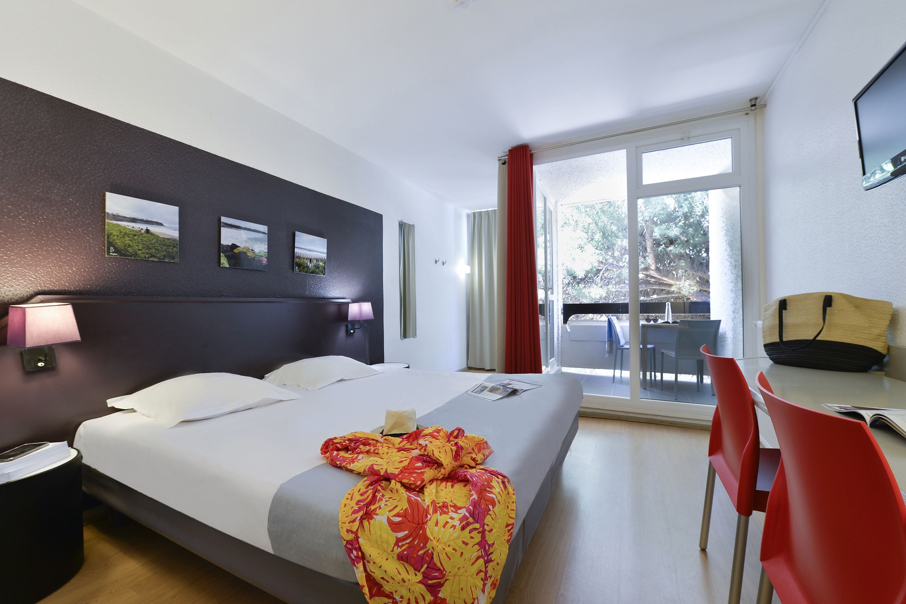 A hotel room with a bed, a desk, a chair, and a window with curtains.