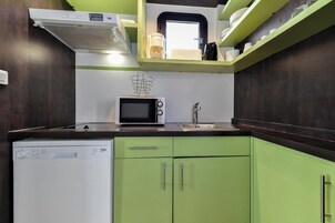 Une cuisine compacte équipée d’un four à micro-ondes, d’un évier et d’un lave-vaisselle.