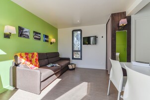 Un salon moderne avec un canapé, un téléviseur et un coin repas.
