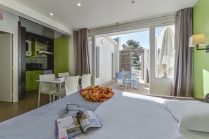 A hotel room with a bed, a dining table, and a kitchenette.