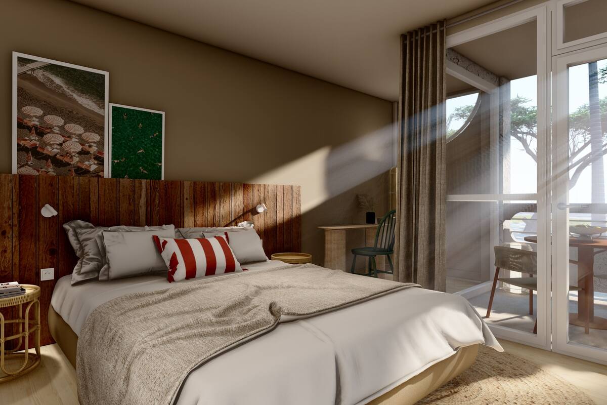 A bedroom with a wooden headboard, a large bed with white bedding, a small round side table, a chair, and a view of the outdoors through a glass door.