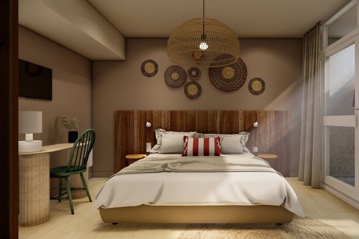 A modern bedroom with a wooden headboard, a large bed with white bedding, a green chair, a desk with a lamp, and a large window with curtains.