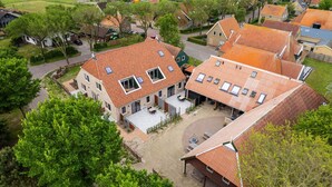 Zona residencial con casas de techo de tejas rojas, un patio empedrado y abundante vegetación.