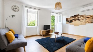 Un salon moderne avec un canapé, une table basse, un téléviseur et des œuvres d’art accrochées au mur.