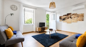 A modern living room with a sofa, a coffee table, a TV, and artwork on the wall.