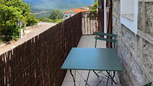 Un balcon avec une table et des chaises, une vue sur les montagnes et une clôture en bois.