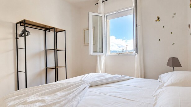 Une chambre à coucher avec un lit, une fenêtre donnant sur un beau paysage, une lampe et une armoire.
