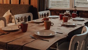A wooden dining table set with plates, cups, and cutlery, with a view of trees and a building through a window. - Hoeve Twente - De Bosuil by Interhome (Heythuysen)